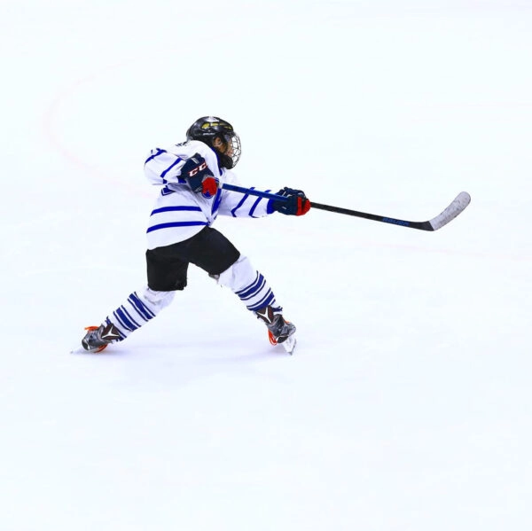 A hockey player is playing an ice hockey where as two hands are holding a hockey stick .