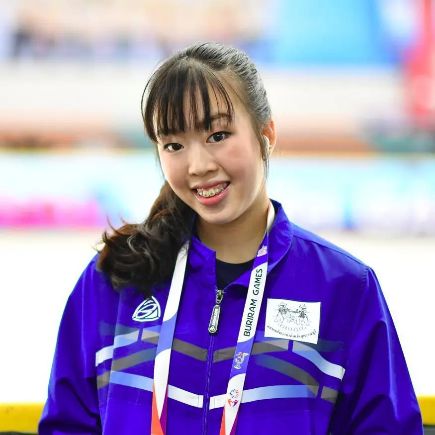 A woman figure skater coach of IWIS in blue jacket.