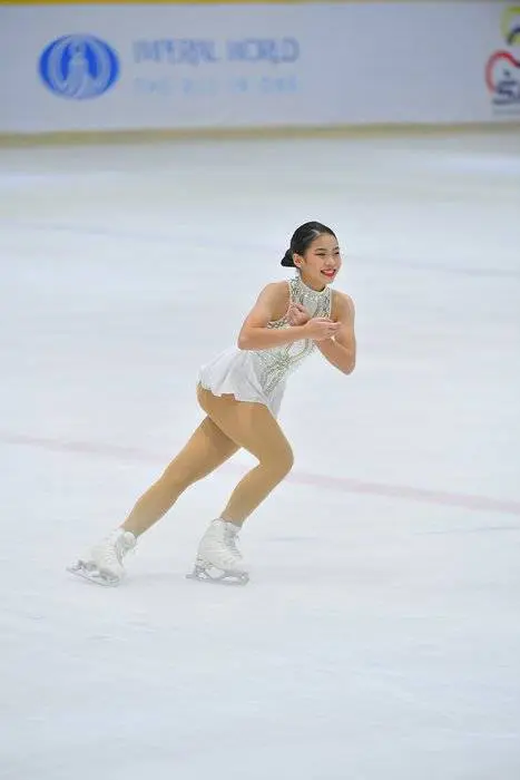 woman in white dress is figure skating on ice