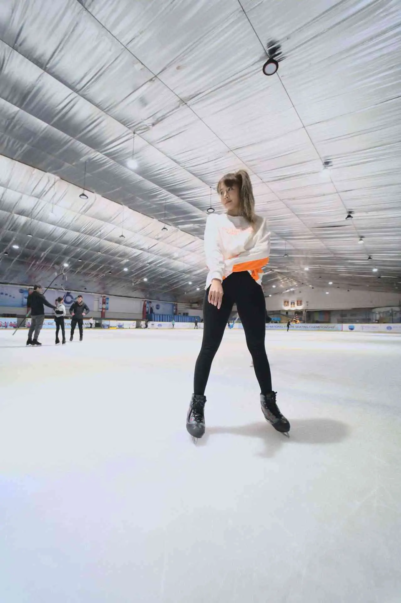 woman put in skating shoes standing on ice in ice rink